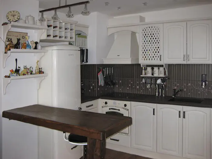Kitchen Nellie – white kitchen with a dark engineered stone top, rounded doors and an oak dining top, photo 1